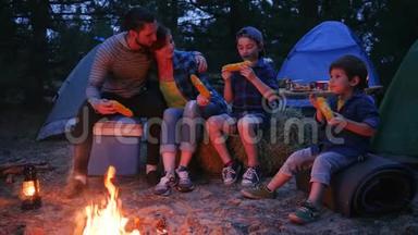 在大自然的火焰附近用餐，<strong>一家人</strong>享用含盐的玉米，户外野餐，<strong>野营</strong>，爸爸妈妈和儿子吃